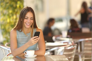 Woman sitting at a cafe table using her phone