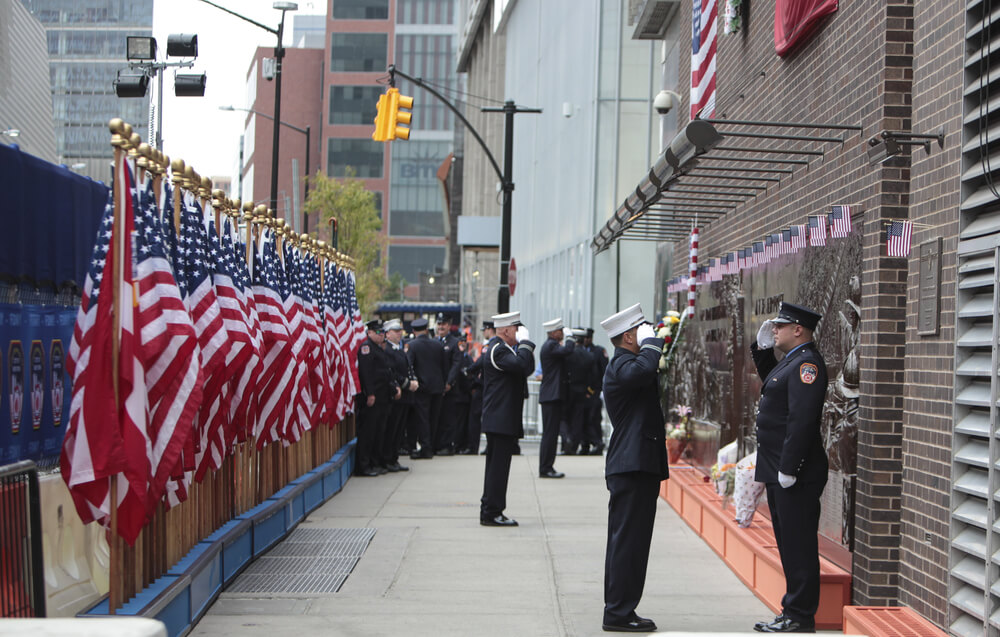 Men saluting in front of September 11 memorial