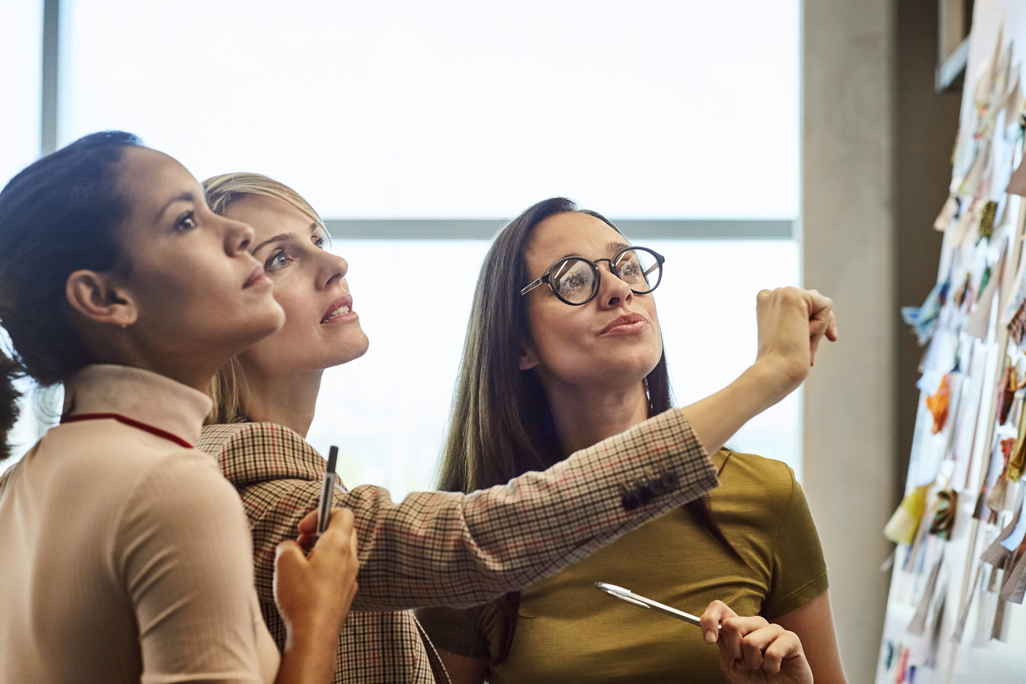 Businesswomen looking at fabric samples on presentation board. Confident female colleagues are working in textile factory. They are wearing smart casuals in office.