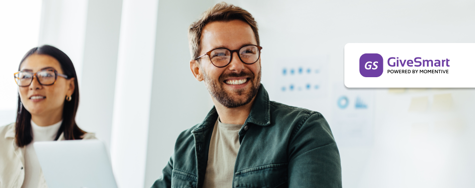 Man in glasses looks to right, while woman on laptop looks forward
